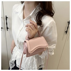 Detailed view of a pink mini crossbody bag featuring a unique wave-shaped flap and thin strap