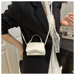 Detail of white mini crossbody bag with leather top handle and shoulder strap