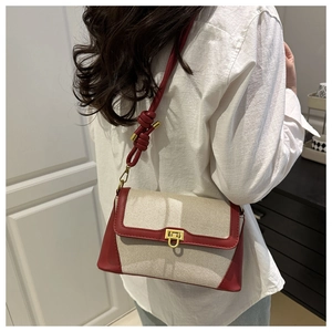Detail of canvas shoulder bag with burgundy leather trim and gold metal clasp
