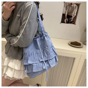 Detail of blue and white gingham tote bag featuring ruffle layers and drawstring design