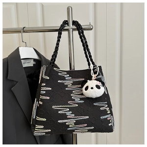 Détail du sac cabas noir avec broderie vagues colorées et charmant pendentif panda