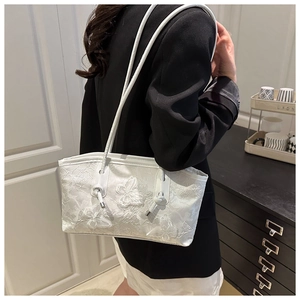 Detailed view of white lace shoulder bag featuring 3D butterfly embroidery texture