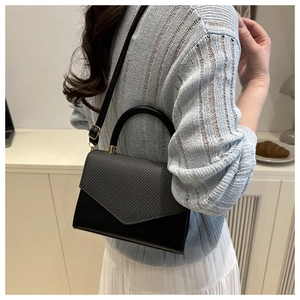 Détail d'un sac à main bicolore avec poignée anneau métallique et bandoulière réglable