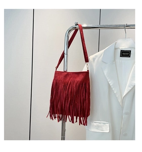 Detail of red suede shoulder bag featuring long fringe tassels and a wide matching strap