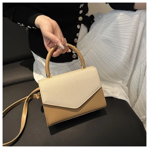 Détail d'un sac à rabat bicolore tressé beige avec base en cuir kaki et poignée