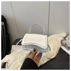 Close-up of a white textured mini handbag showing fine stitching and top handle details