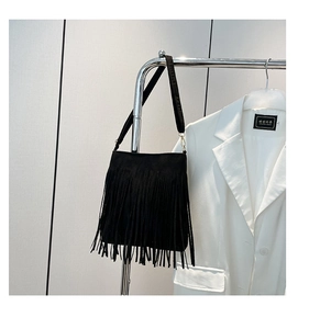 Detail of black matte PU leather bag with dense bohemian style fringes on a metal hanger