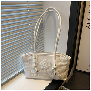 Detailed view of the white lace embroidery and 3D bow accent on this elegant tote bag