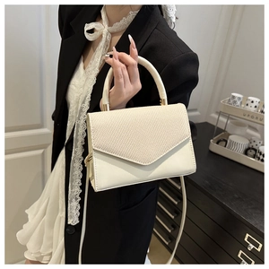 Détail du sac crème avec rabat en texture tissée et finitions dorées porté par mannequin
