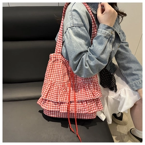 Detail of red gingham tote bag featuring triple-layered ruffles and red drawstrings