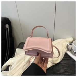 Detail of light pink mini crossbody bag featuring unique wavy edge flap and silver hardware
