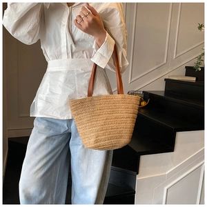 Detail of hand-woven straw tote with premium brown leather straps on a casual outfit