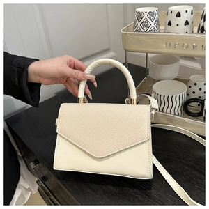 Détail du rabat en cuir crème et tissé sur un sac à main bandoulière chic et minimaliste