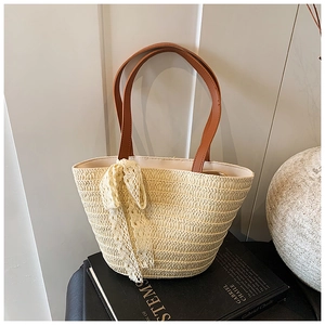 Detail of hand-woven straw tote with delicate lace bow and brown leather straps
