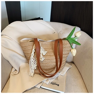 Detail shot of the woven straw tote bag with elegant lace trim and leather straps