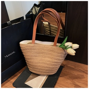 Detail of hand-woven straw tote bag with brown leather straps and white inner lining