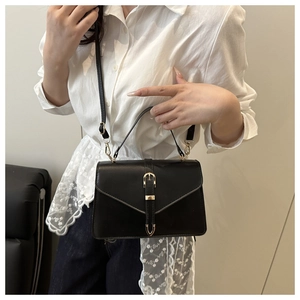 Détail d'un sac à main carré noir avec fermoir doré et bandoulière en cuir élégante