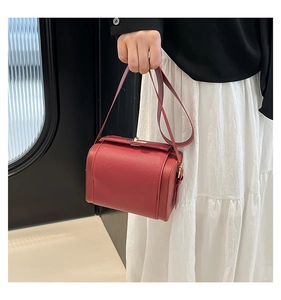 Detail of red lychee grain leather vintage handbag with elegant gold metal clasp