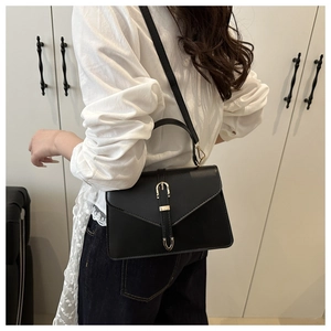 Vue latérale du sac en cuir noir mat avec boucles dorées porté par un mannequin