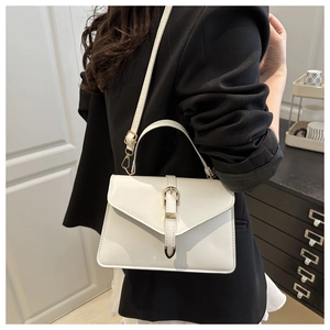 Detailed side view of white faux leather crossbody bag with gold V-shaped metal buckle