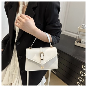 Detail of white envelope-style handbag with gold buckle and adjustable strap