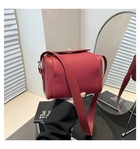 Close-up of red lychee pattern leather handbag with golden hardware and wide strap