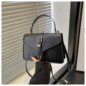 Detail of black faux leather handbag with envelope flap and gold buckle hardware