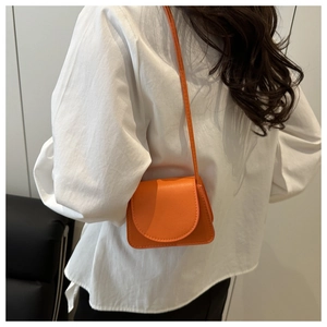Detail einer leuchtend orangefarbenen Mini-Umhängetasche mit Lederstruktur auf weiß