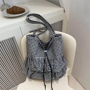 Gingham checkered tote bag with double ruffles and drawstring closure on a white chair