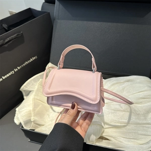 Minimalist light pink crossbody square bag with a wave design lid and top handle
