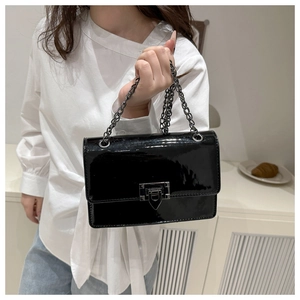 Detail of glossy black patent leather flap bag with silver rivet buckle and metal chain