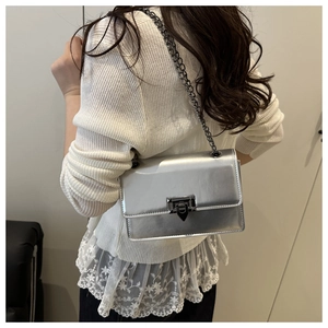 Model view of a silver metallic crossbody bag with chain strap and geometric lock