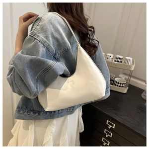 Model view of a white minimalist hobo shoulder bag with embossed fashion text detail