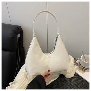 Detail view of a cream-colored crescent hobo bag with Fashion lettering and smooth texture
