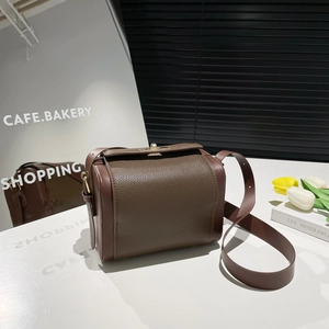 Deep brown lychee textured leather crossbody bag with golden hardware on a white stand