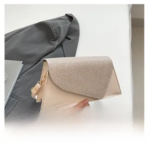 Detail view of a beige sequined flap crossbody bag styled with a gray suit and magazine