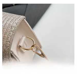Detail of the golden D-ring metal buckle and sequin finish on the leather strap bag