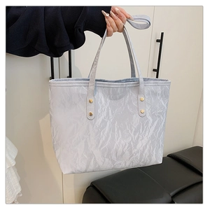 Detail of metallic crinkle texture tote bag with golden rivets and slim handles