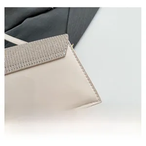 Close-up of beige patent leather shoulder bag featuring sparkly glitter fabric flap