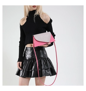 Détail d'un sac à bandoulière rose à paillettes argentées porté sur une tenue noire