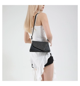 Détail d'un sac bandoulière noir à paillettes avec coutures blanches sur un mannequin