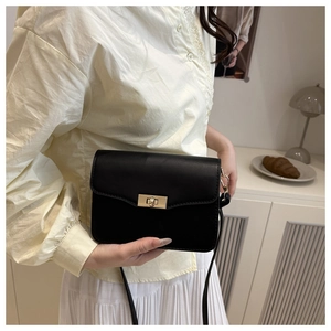 Lifestyle shot of a black minimalist rectangular shoulder bag with golden lock on a model