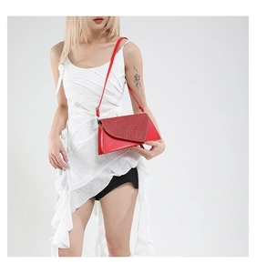Gros plan d'un sac bandoulière rouge pailleté avec rabat et boucle dorée sur modèle
