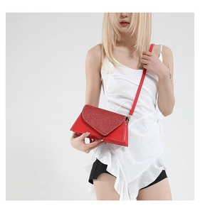 Sac à bandoulière rouge avec couvercle en strass porté par un mannequin en robe