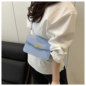Detail of light blue faux leather crossbody bag with golden rectangular turn-lock closure