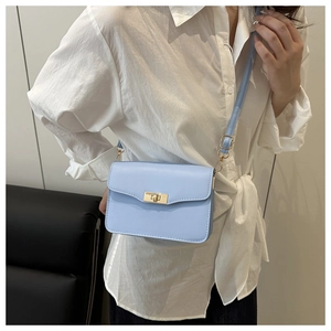 Close-up of light blue square shoulder bag with golden rotary lock on model