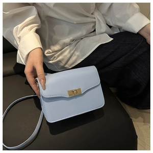 Detail of light blue square bag featuring a gold twist lock and neat stitching