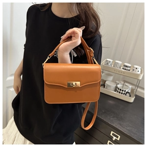 Close-up of orange leather crossbody bag with a gold metal twist lock closure