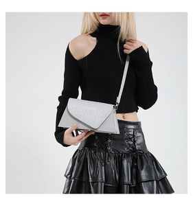 Silver envelope crossbody bag with glitter flap worn by a model in black attire
