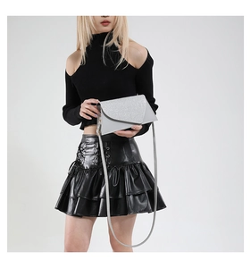 Sac à bandoulière enveloppe gris chic avec paillettes argentées porté par un mannequin